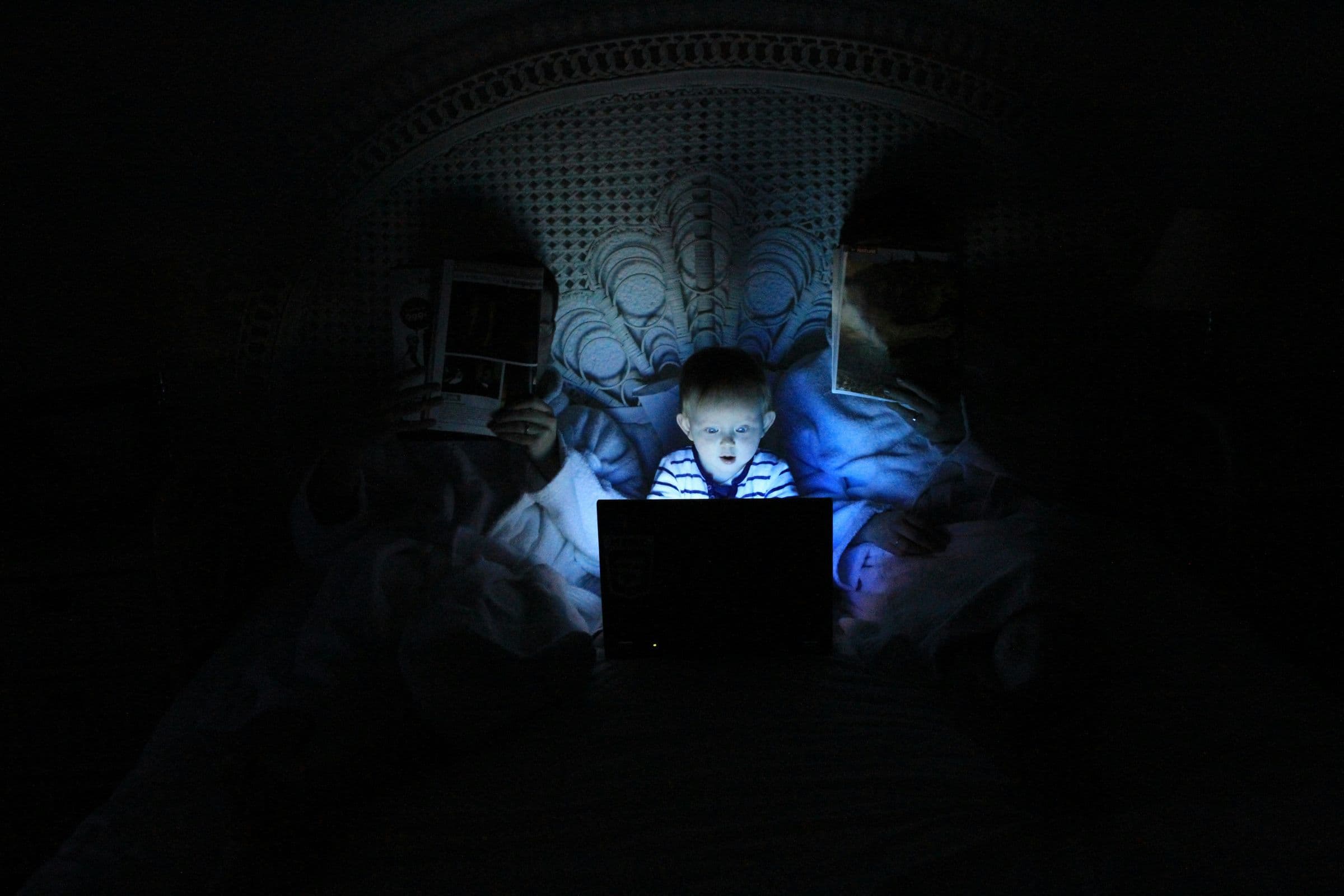 Kleinkind sitzt im Dunkeln an einem Laptop
