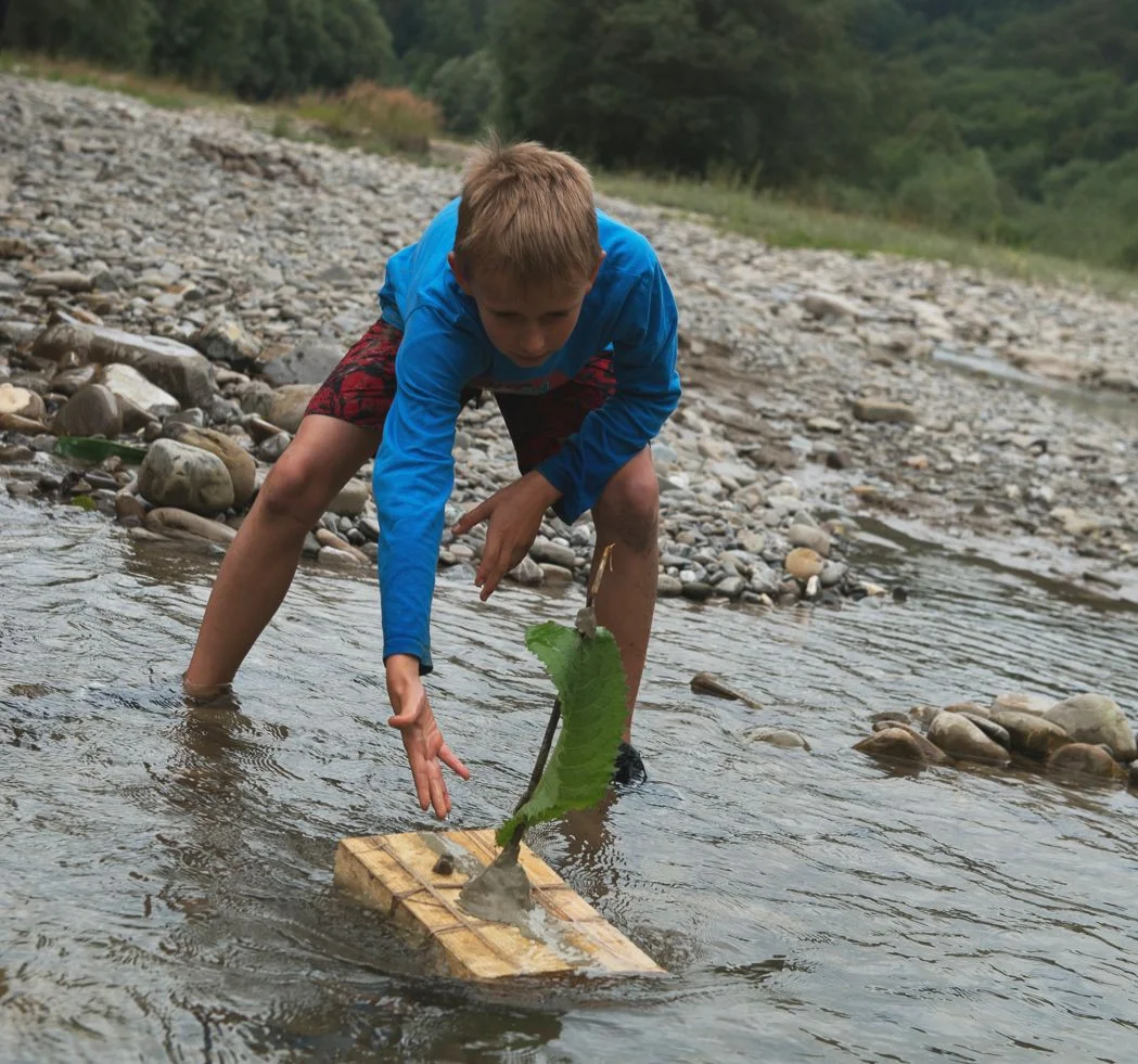 Junge schickt Floss aufs Wasser