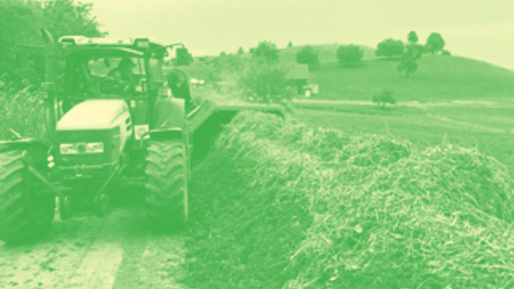 Traktor mit Kompostwender fährt Kompostmiete entlang.