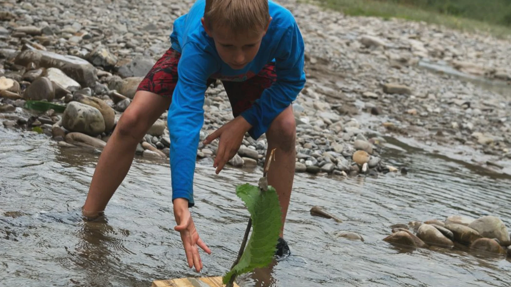 Junge schickt Floss aufs Wasser