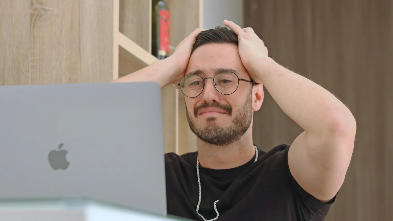 Mann sitzt vor dem Laptop und schlägt die Hände über dem Kopf zusammen. Sein Gesichtsausdruck verrät, dass er einen Fehler gemacht hat.