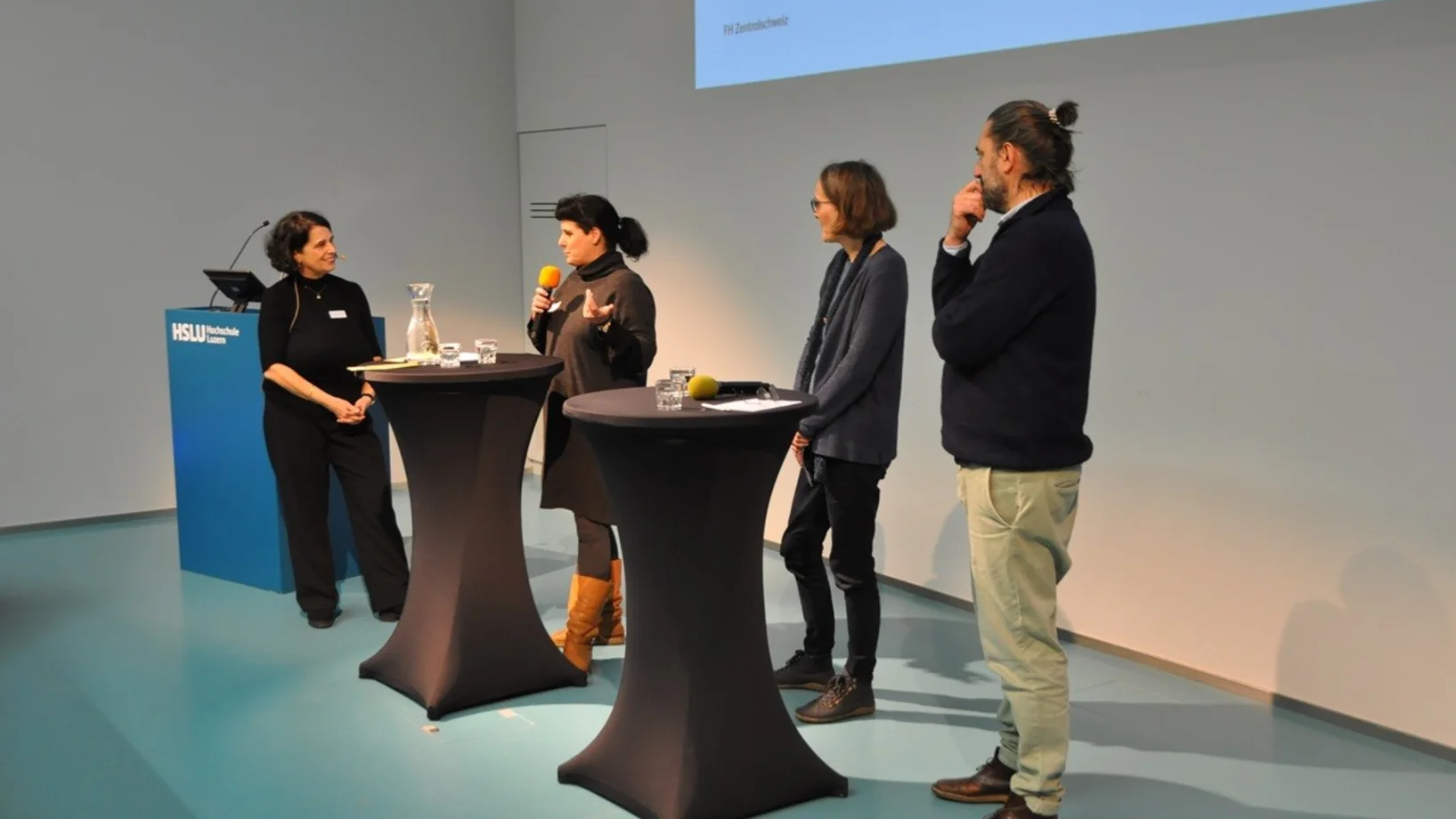 Podium, vier Personen an Stehpult