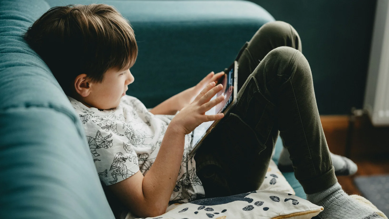 Kind auf dem Sofa, spielt am iPad